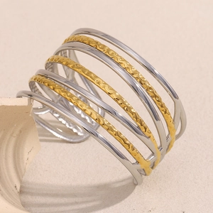 Gros plan sur un bracelet ouvert multicouche doré et argenté avec texture martelée