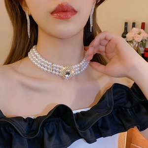 Détail d'un collier de perles à trois rangs avec cristal ovale et boucles d'oreilles