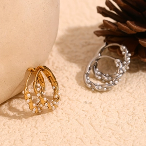 Macro shot of 18K gold plated twisted hoop earrings with elegant pearl detail accents