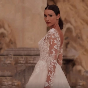 Elegant white lace wedding dress with long sleeves and cathedral train in outdoor setting