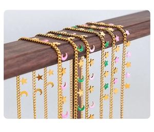 Detailed close-up of gold star and moon charms with pink and green enamel inlay