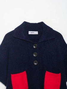Detail of dark blue knit cardigan with lapel collar and vibrant red front pockets
