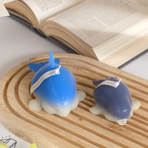 Orca and dolphin shaped scented candles in gradient blue and purple on wooden tray