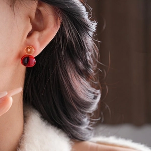 Elegant amber and deep red resin double gourd earrings worn by a model in soft light