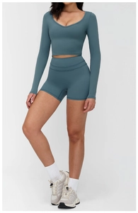 Detail of grey-blue two-piece yoga set featuring long sleeve V-neck top and high waist shorts