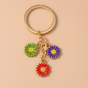 Detail of gold keychain with three colorful enamel daisy flower charms in green, red and purple