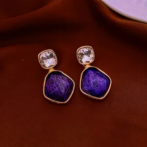 Vintage brushed resin earrings with gold accents and purple stones on brown silk background