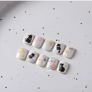 Macro detail of 3D embossed cat and fruit motifs on pearlescent white press-on nails