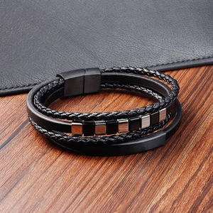 Detail view of multi-layer black braided leather bracelet with square beads on wood