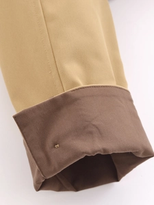 Vue détaillée des poignets du trench-coat kaki avec contraste brun et détail en métal