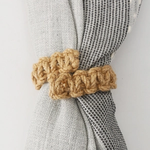Handwoven cotton linen curtain tieback with a rustic braided design on a neutral fabric