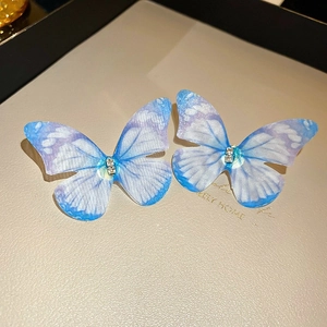Détail des boucles d'oreilles papillon dégradé bleu avec cristaux sur support cuir