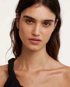 Close-up of a gold heart pendant necklace with shimmering crystals on a female model