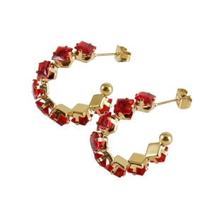 Detail view of gold hoop earrings with square-cut red zircon stones on white background
