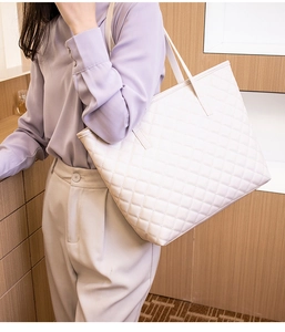 Lifestyle shot of white quilted tote bag with dual shoulder straps for daily commute use