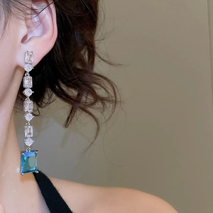 Close-up of long tassel earrings with clear zircon and sky blue rectangular gemstones