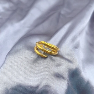 Detail of adjustable golden multi-layer spiral ring with two clear zircons on silk fabric