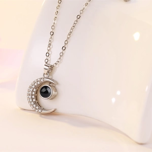 Macro shot of silver crescent moon necklace featuring micro-pave zircons and projection gem