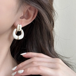 Detail of vintage French gold-plated horseshoe earring with white enamel finish