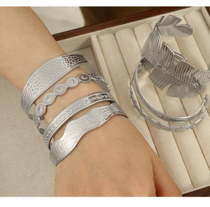 Stackable silver adjustable bangles featuring star, wave and feather patterns