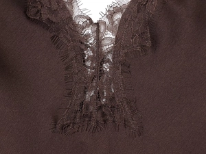 Detailed macro view of delicate eyelash lace trim on a dark brown satin dress neckline