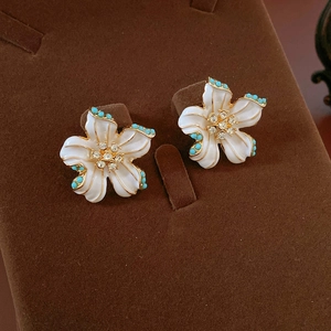 Détail de boucles d'oreilles vintage fleurs aux pétales blancs et perles turquoise