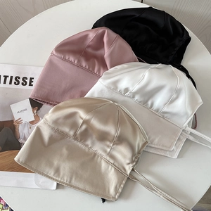 Macro shot showing four silk satin bucket hats in black, pink, white, and champagne gold