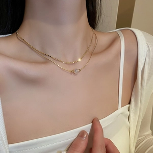 Close-up of double-layer golden chain necklace featuring rainbow iridescent pearls
