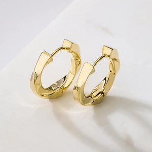 Minimalist gold plated geometric hoop earrings on a white marble background