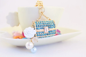 Close-up of blue rhinestone handbag keychain with white rose and pearl charms