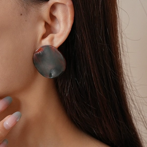 Gros plan d'un modèle portant de grandes boucles d'oreilles rondes en acrylique léopard