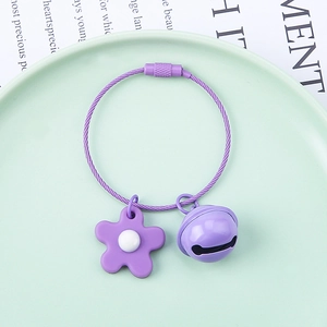 Detail of purple soft glue flower keychain with wire loop and bell on a green plate