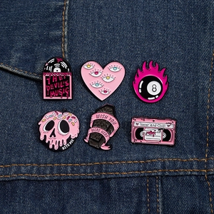 Detailed set of 6 pink and black punk enamel pins displayed on blue denim fabric background