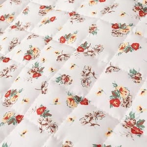 Detailed macro view showing the quilted floral pattern and cotton texture on garment fabric