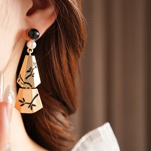 Detail of elegant gold branch tassel earrings with pearls on a model wearing them