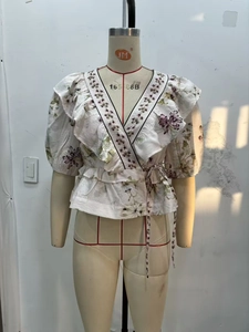 Detail view of V-neck floral wrap top with embroidered trim and puff sleeves