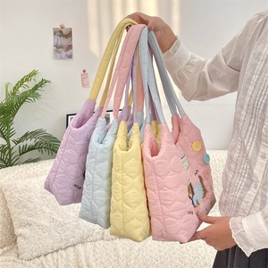 Detalle de bolsos tote acolchados en tonos pastel rosa, azul, amarillo y púrpura