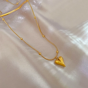 Detailed shot of a gold heart pendant necklace on an elegant white silk background