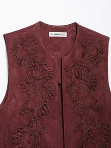 Dettaglio del gilet in camoscio bordeaux con elaborati ricami floreali 3D su sfondo bianco
