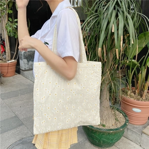 Outdoor view of daisy pattern canvas tote bag showing size and shoulder fit on model