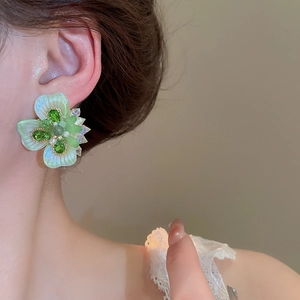 Macro view of crystal flower earring with green petals and central pearl detail