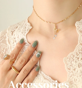 Detail of gold butterfly tassel necklace and rings set with sparkling zircon accents