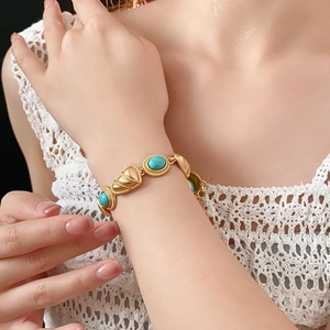 Bracelet doré vintage avec pierres turquoise et breloques coquillages sur le poignet