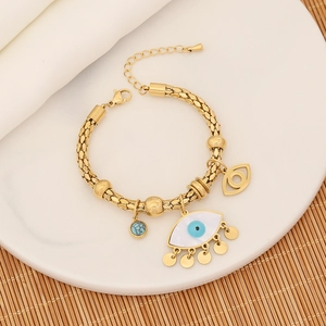 Macro shot of gold evil eye charm bracelet with white mother of pearl on a ceramic tray