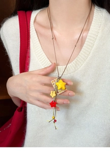 Detail of colorful acrylic star and floral square pendants on a woven cord necklace