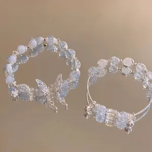 Luxurious crystal butterfly beaded bracelets with floral pendants on a gold mirror surface