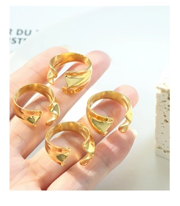 Close-up of four minimalist golden irregular wavy open rings set in titanium steel