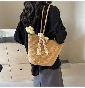 Detailed back view of a woven tote bag with white lace bow on a female model