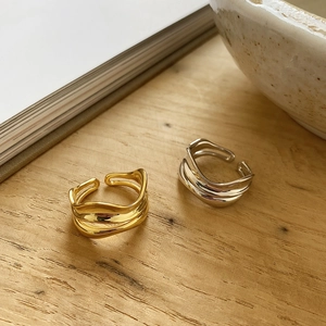 Detail view of wavy multi-layered 925 sterling silver rings on a wooden texture background