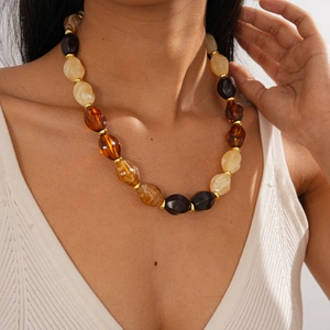 Detail of chunky acrylic oval beads on necklace with golden spacers on a model